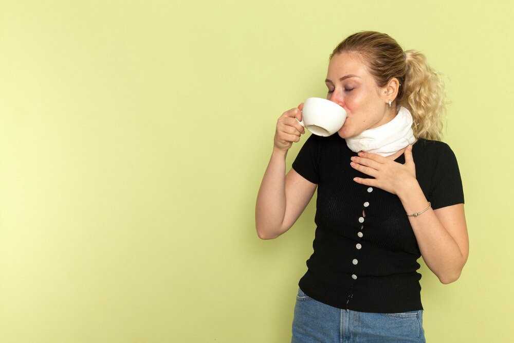 Front view young female feeling very ill and sick holding and drinking cup of coffee on the green wall sickness medicine illness health